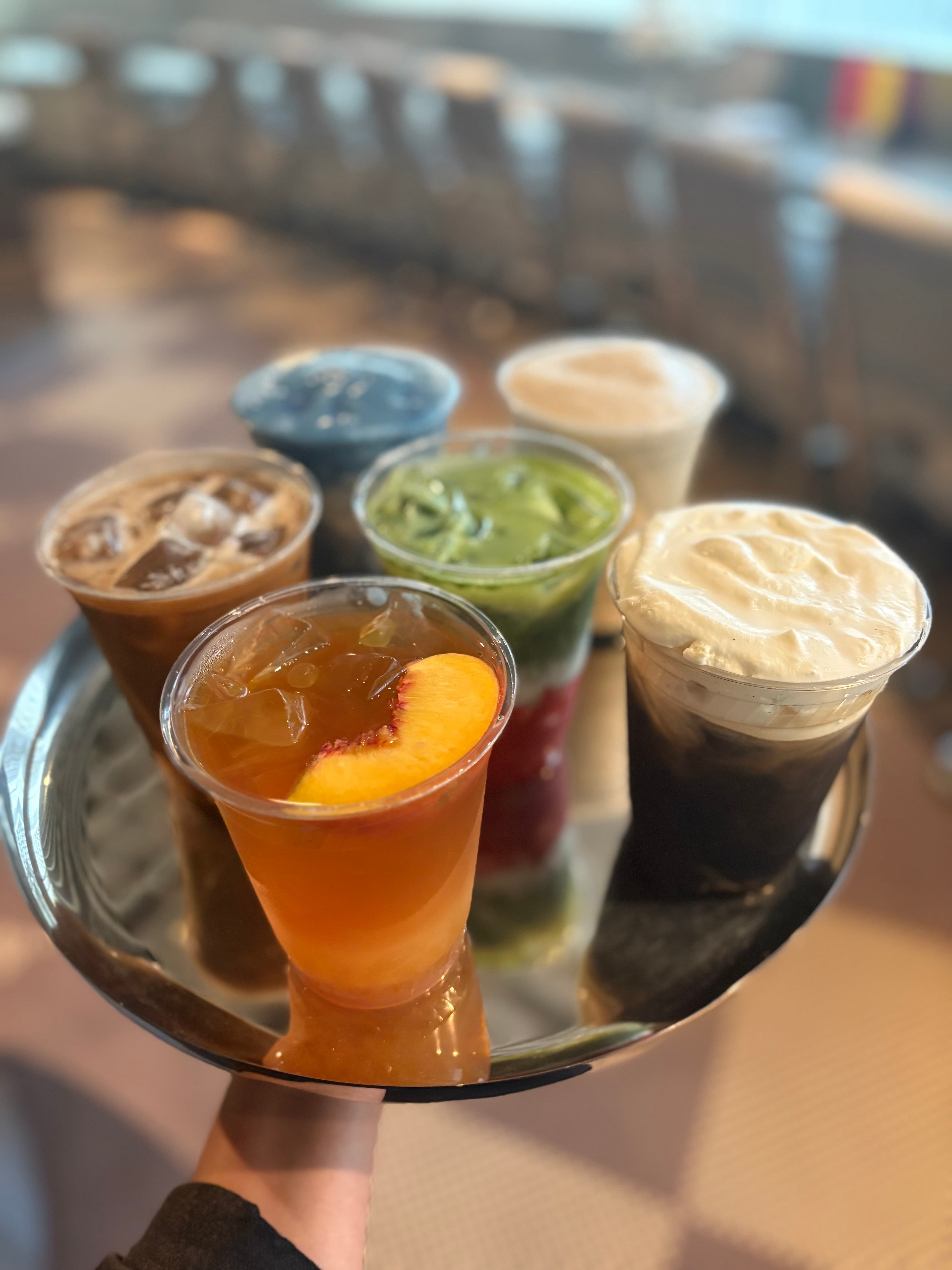 Tray of colorful iced and cream-topped drinks
