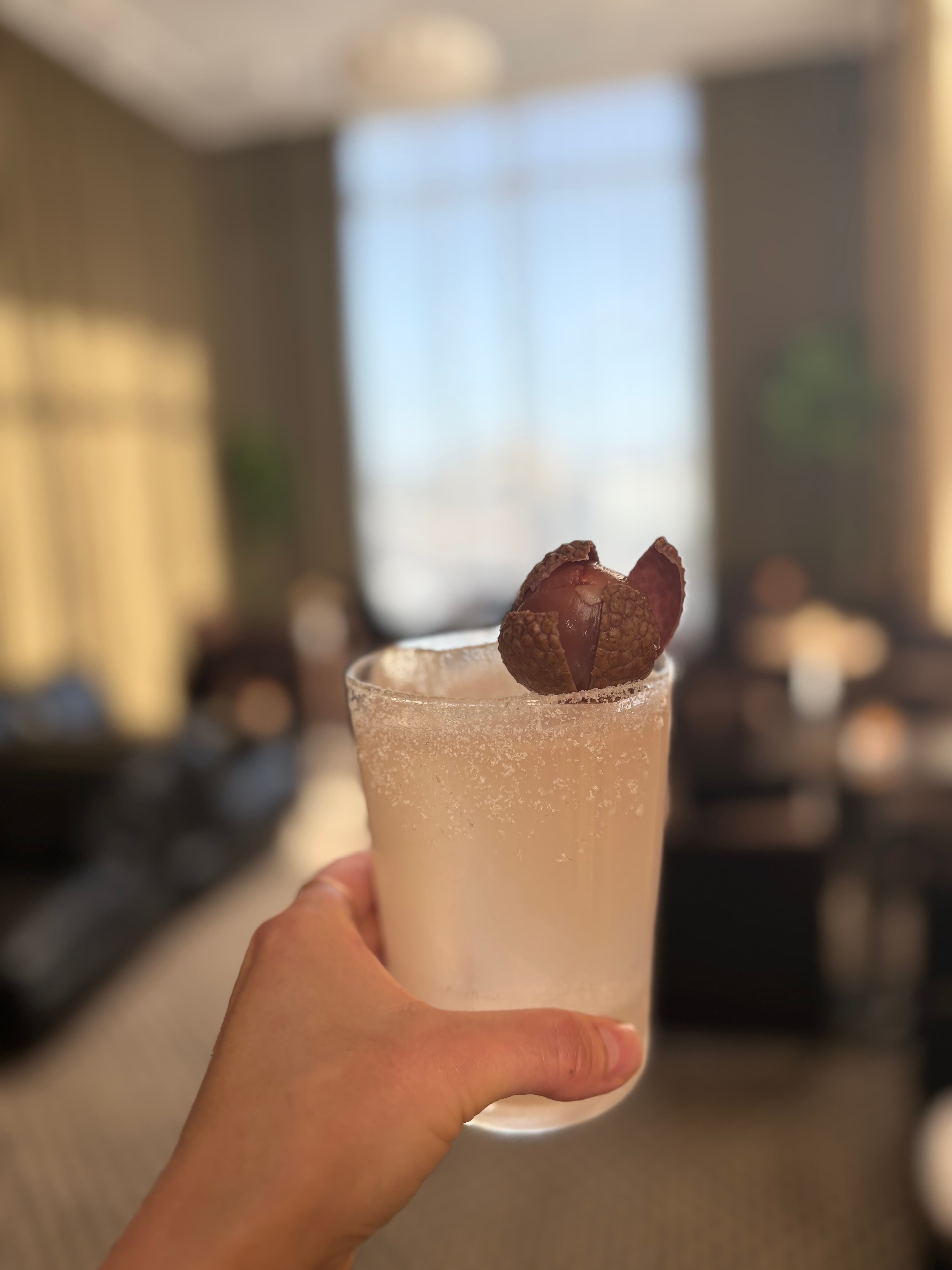 Pale highball with a sugared rim and lychee garnish