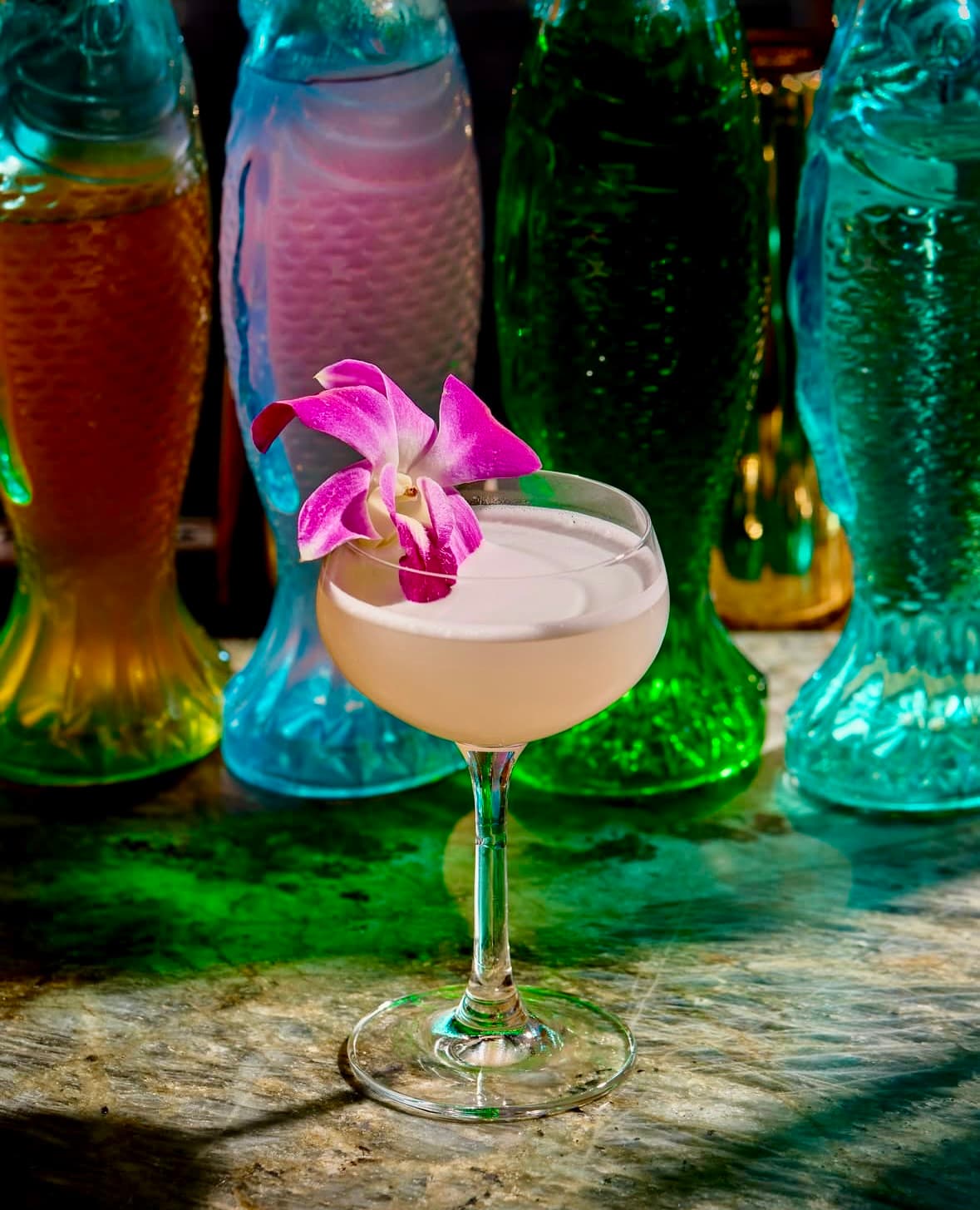 Creamy coupe cocktail garnished with a purple orchid
