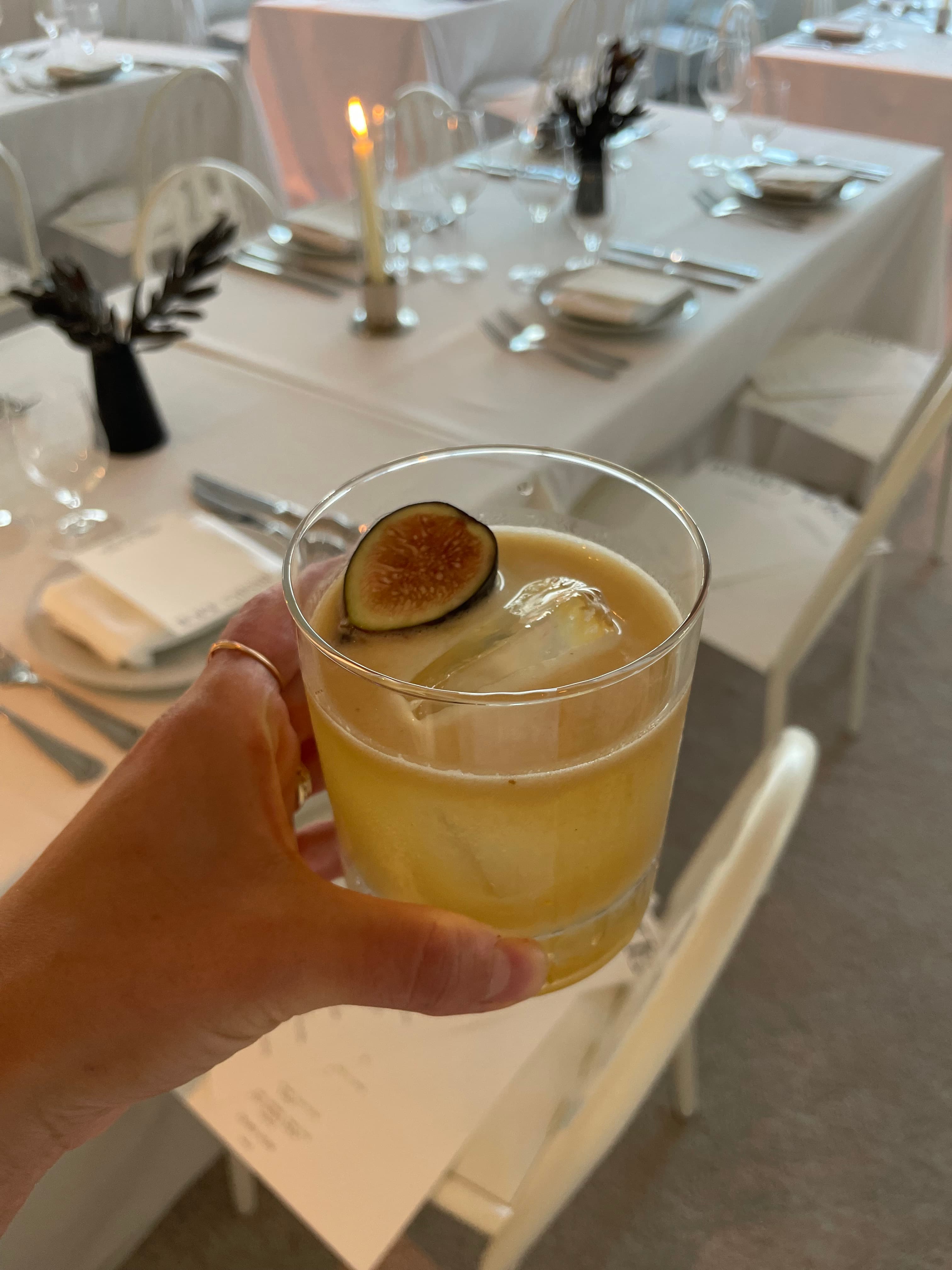 Golden cocktail over a large ice cube garnished with fresh fig