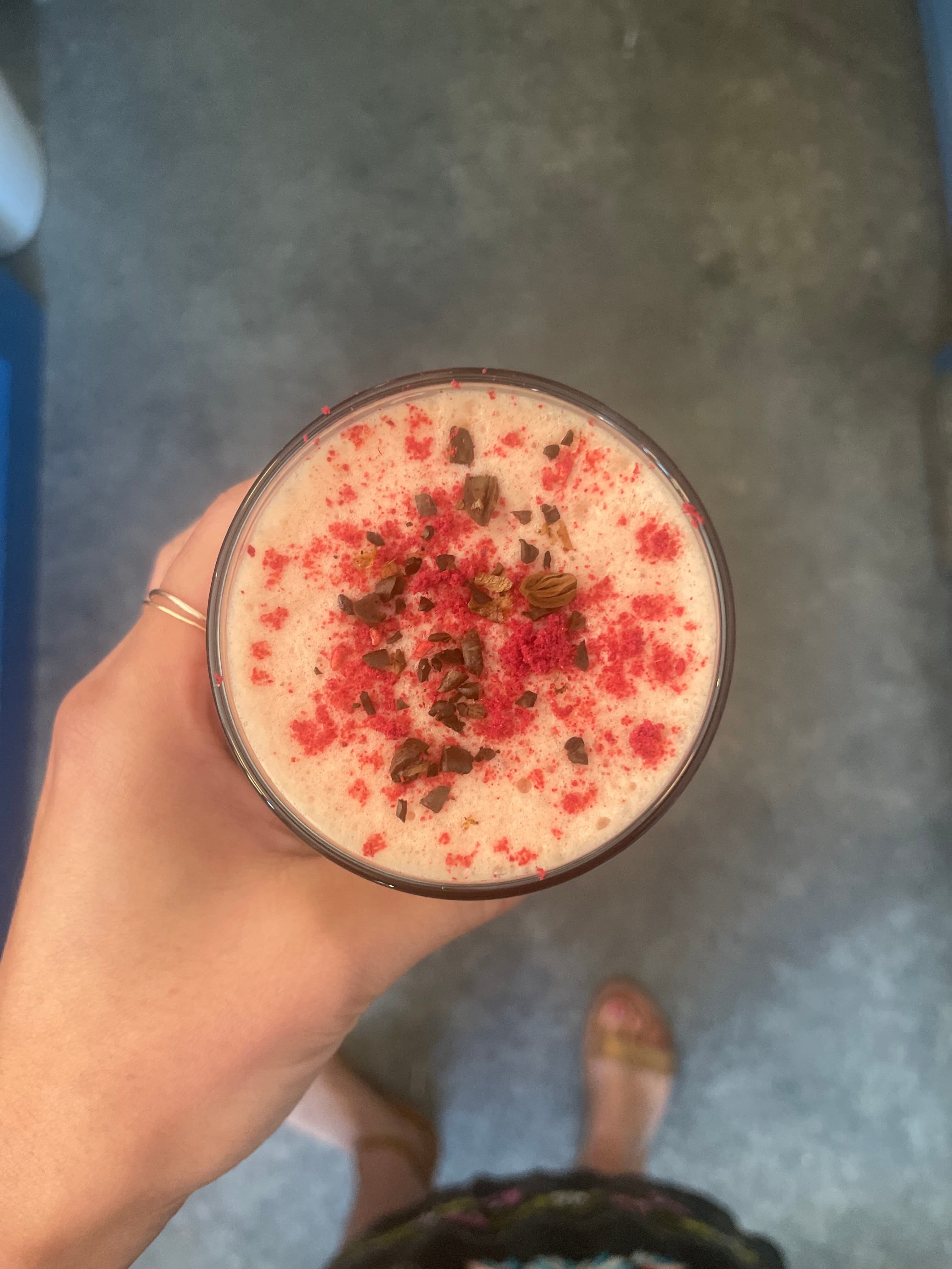 Overhead view of a foamy drink dusted with raspberry and cacao