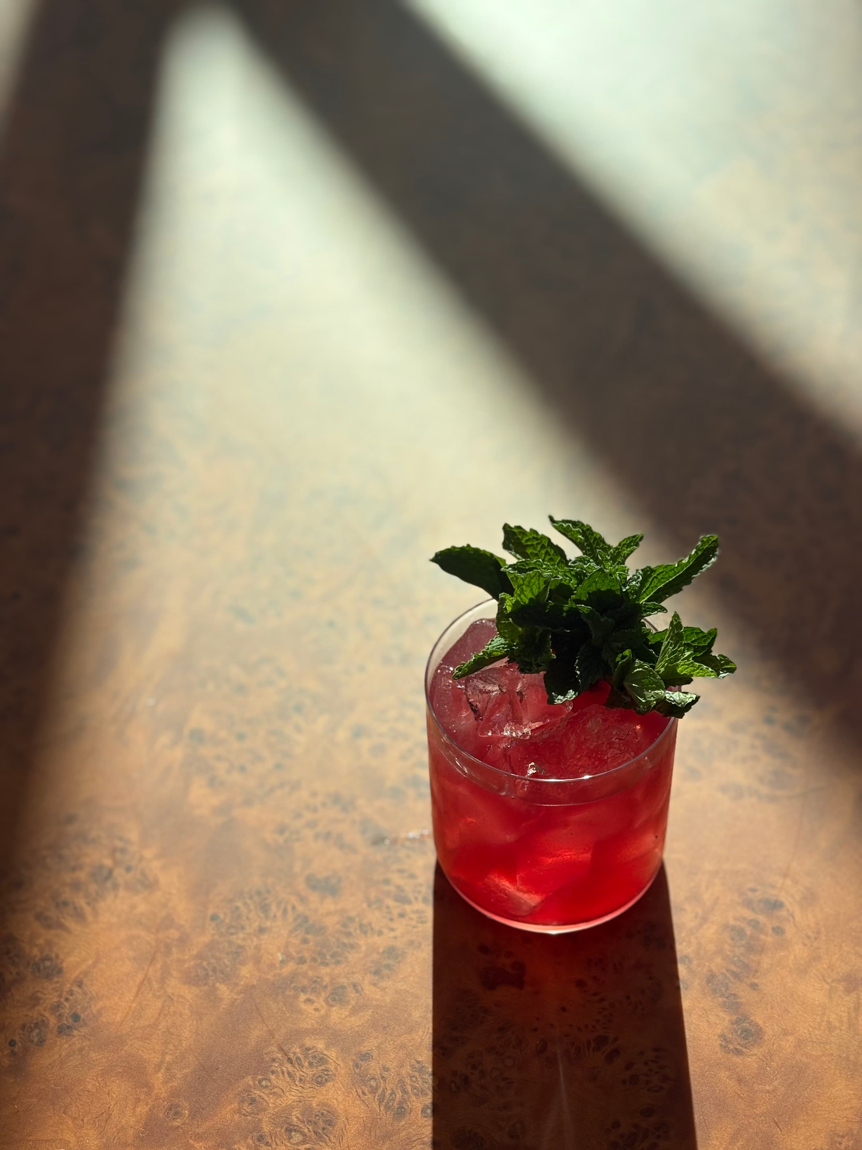 Red cocktail over ice with a generous bouquet of mint