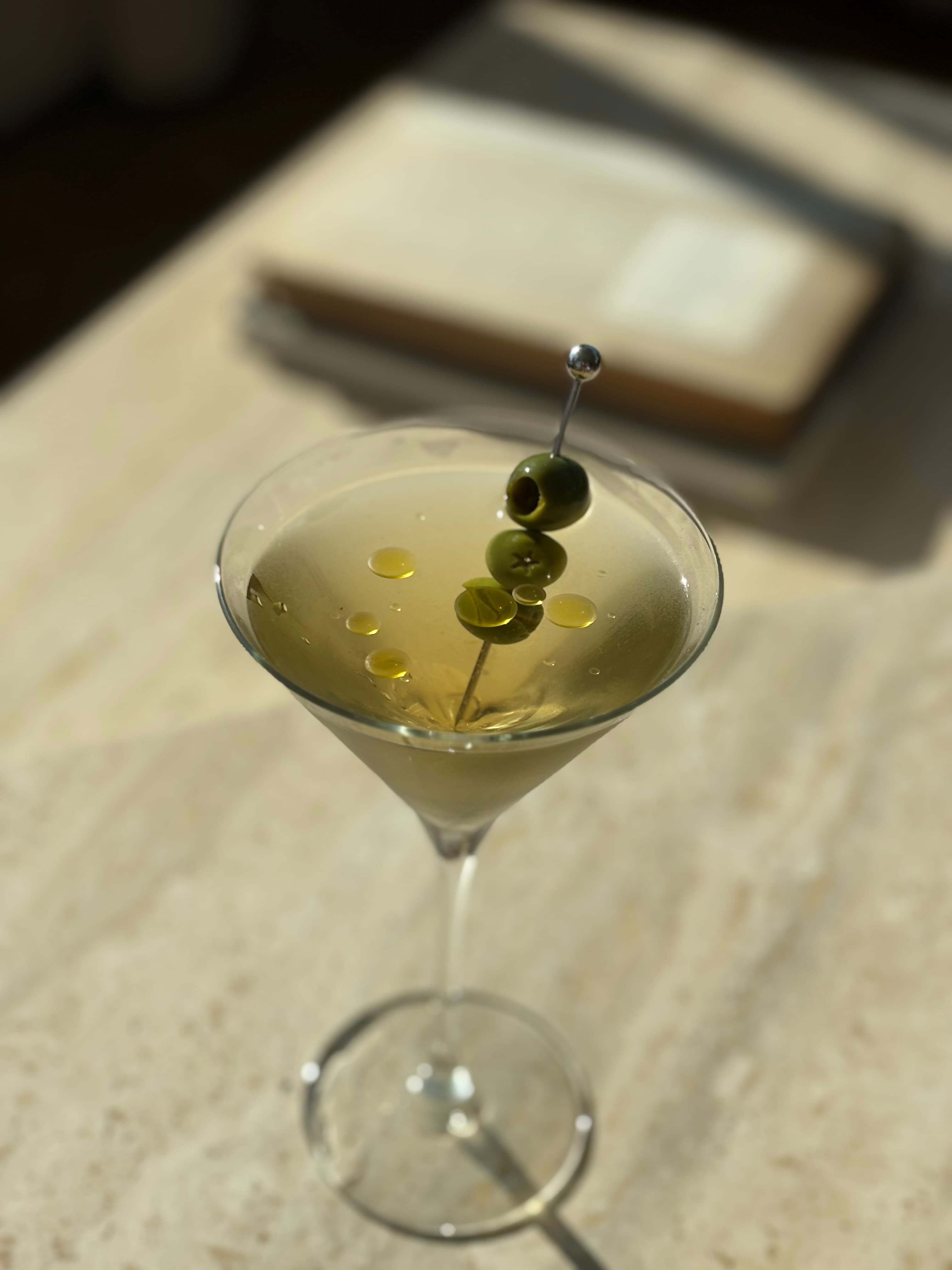 Martini garnished with green olives in warm afternoon light