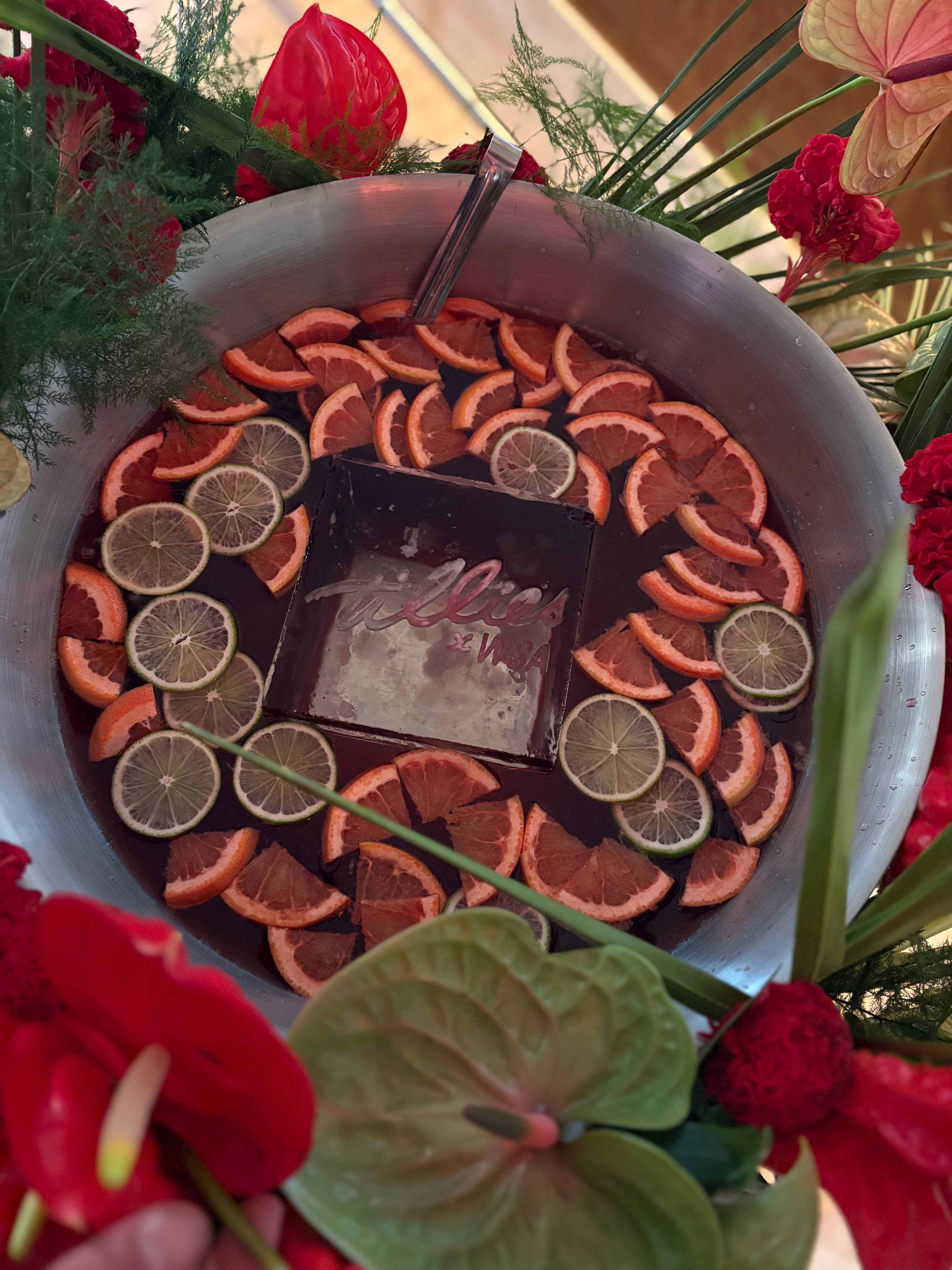 Large citrus punch bowl surrounded by tropical red flowers