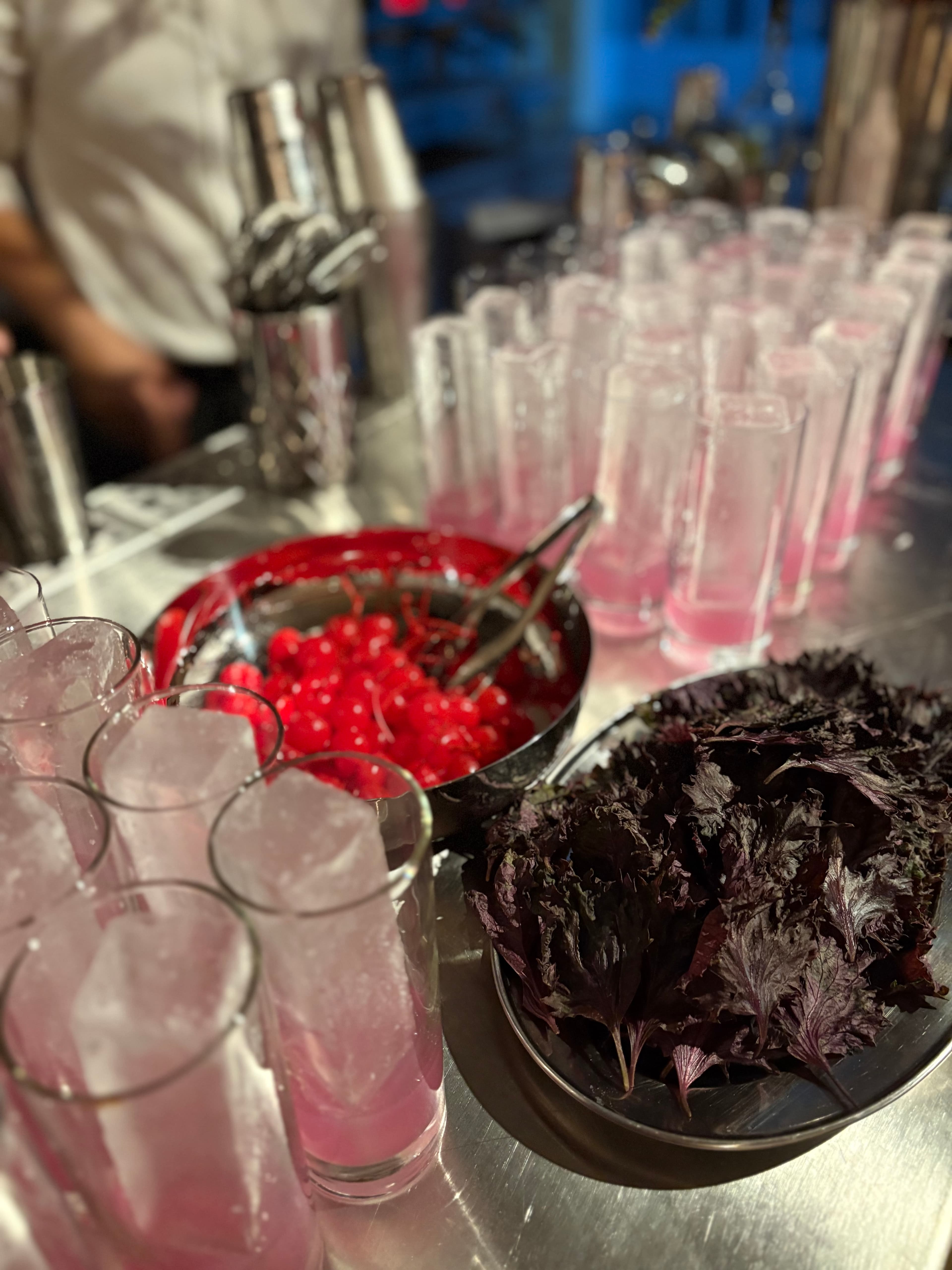 Rows of pale pink highballs beside cherries and purple shiso
