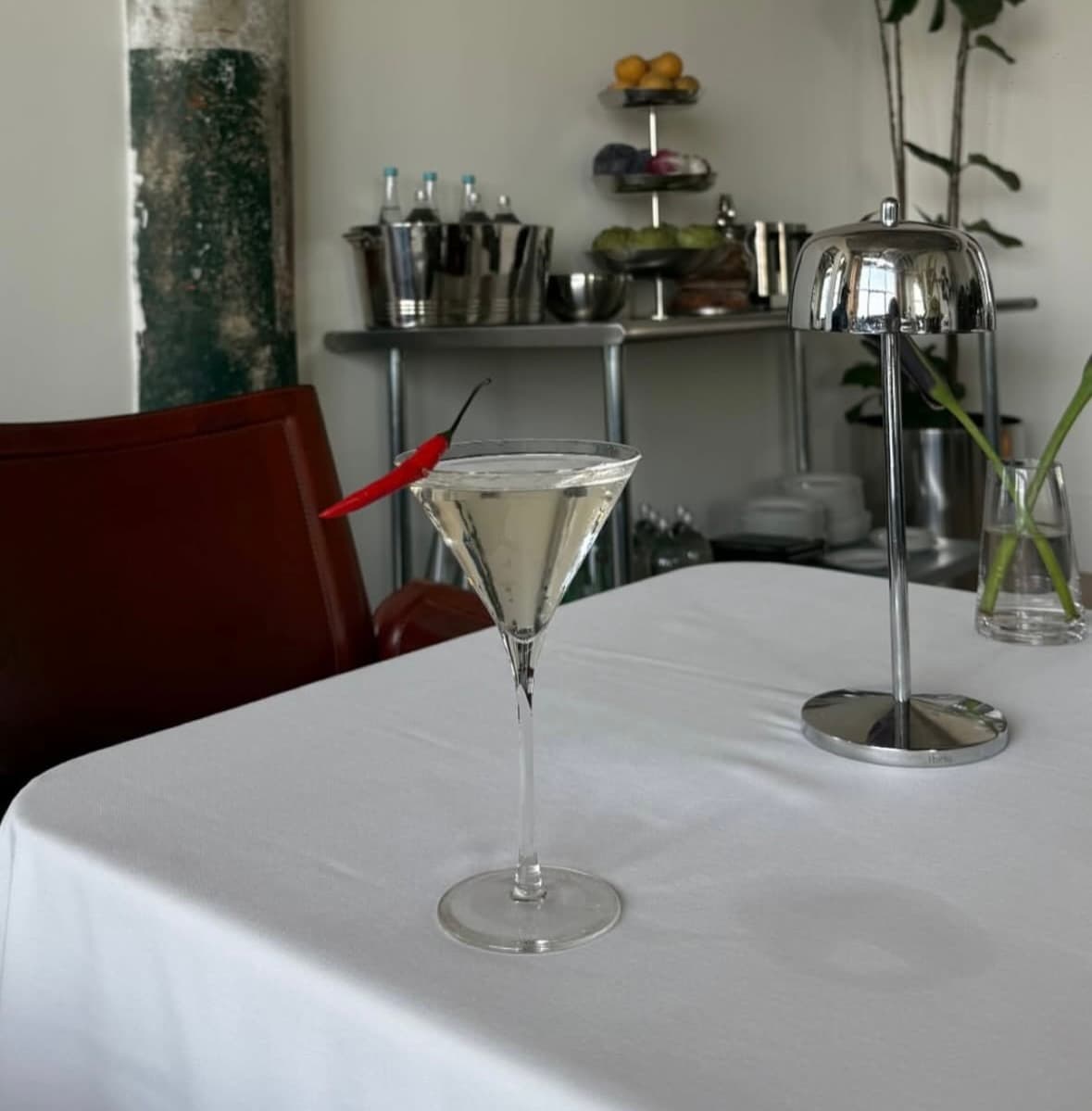 Clear martini with a red chile garnish on a white tablecloth