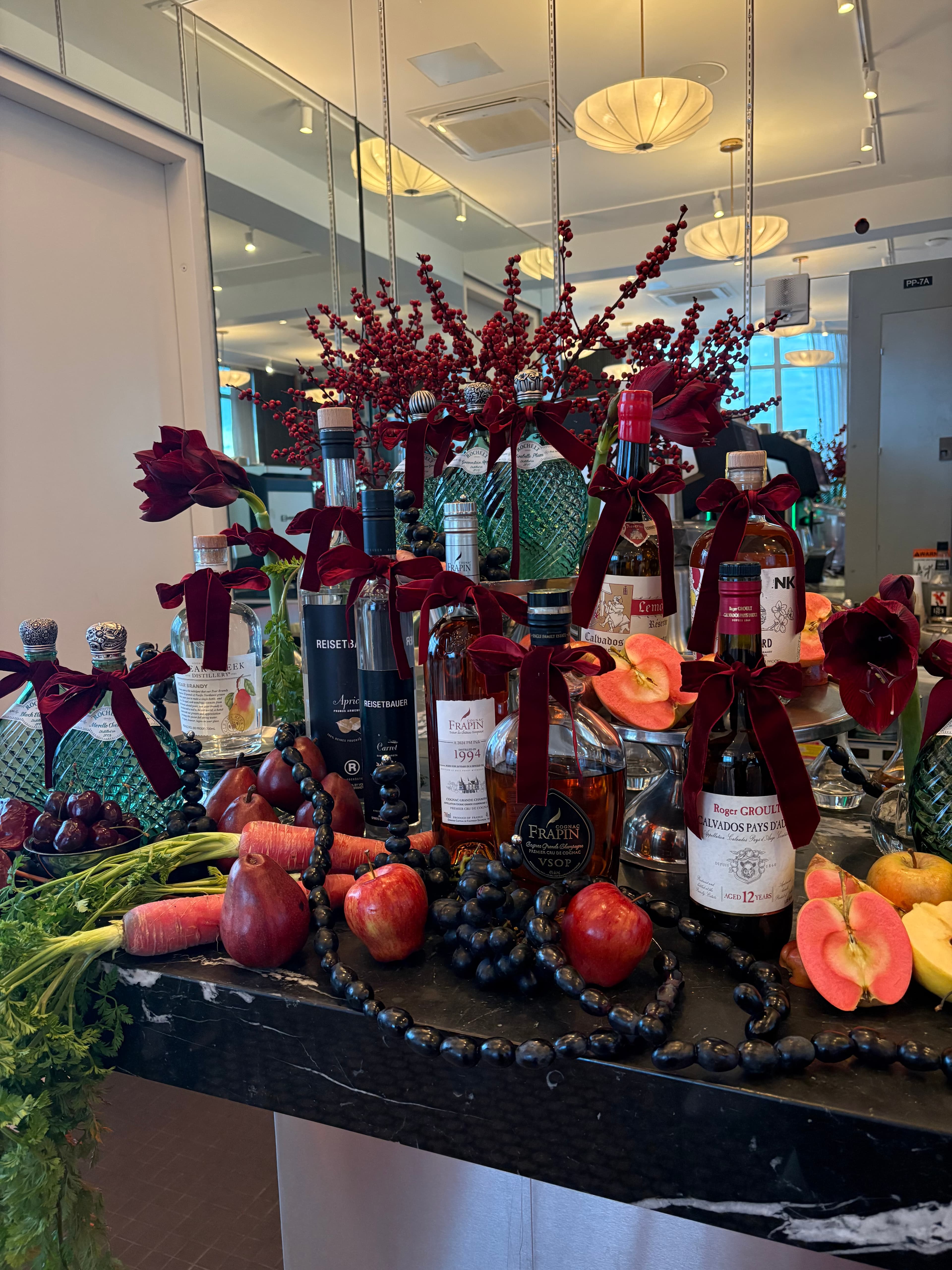 Bottle and fruit installation with burgundy flowers and ribbons