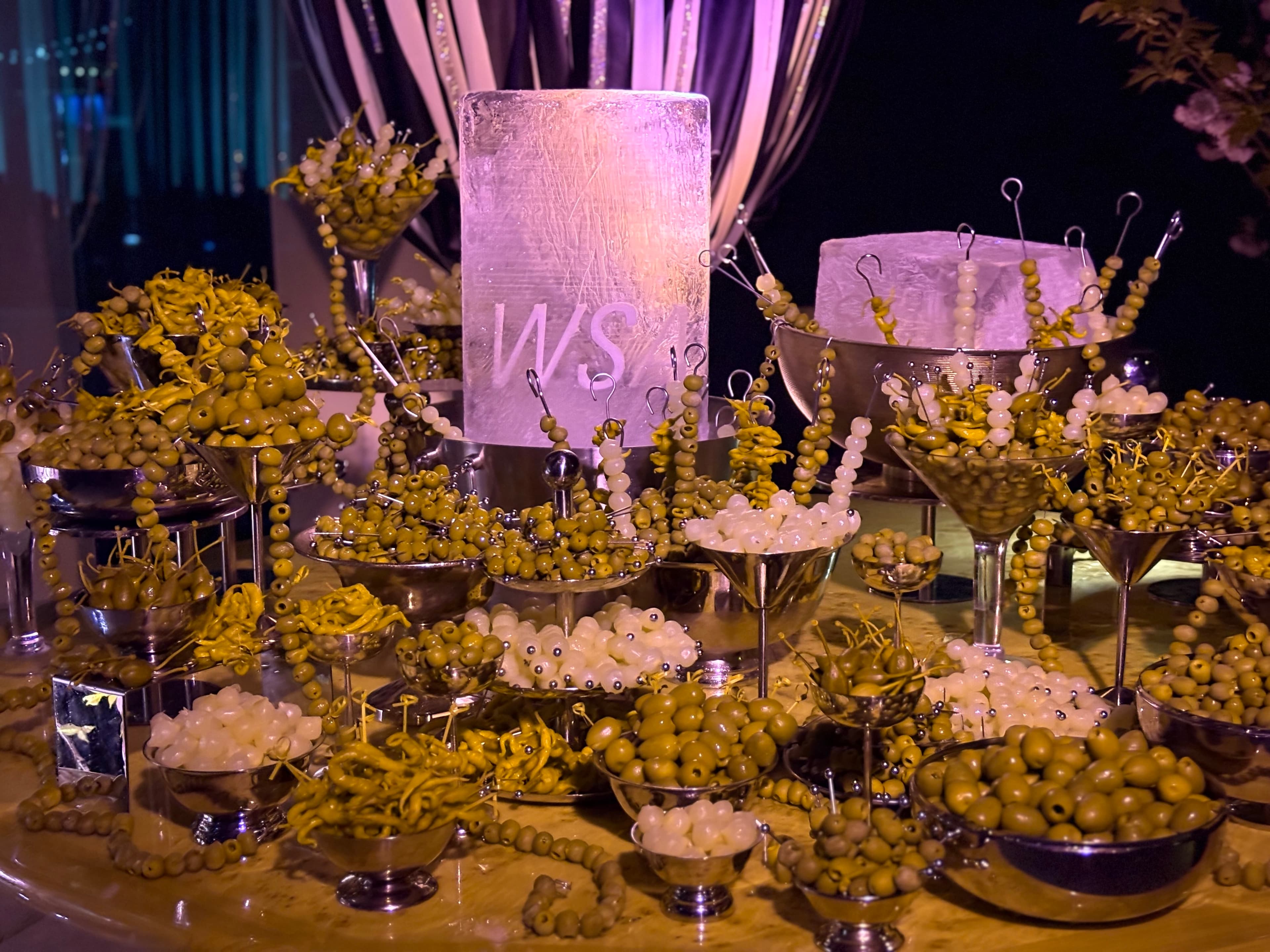 Detail of olives and cocktail garnishes surrounding an ice block