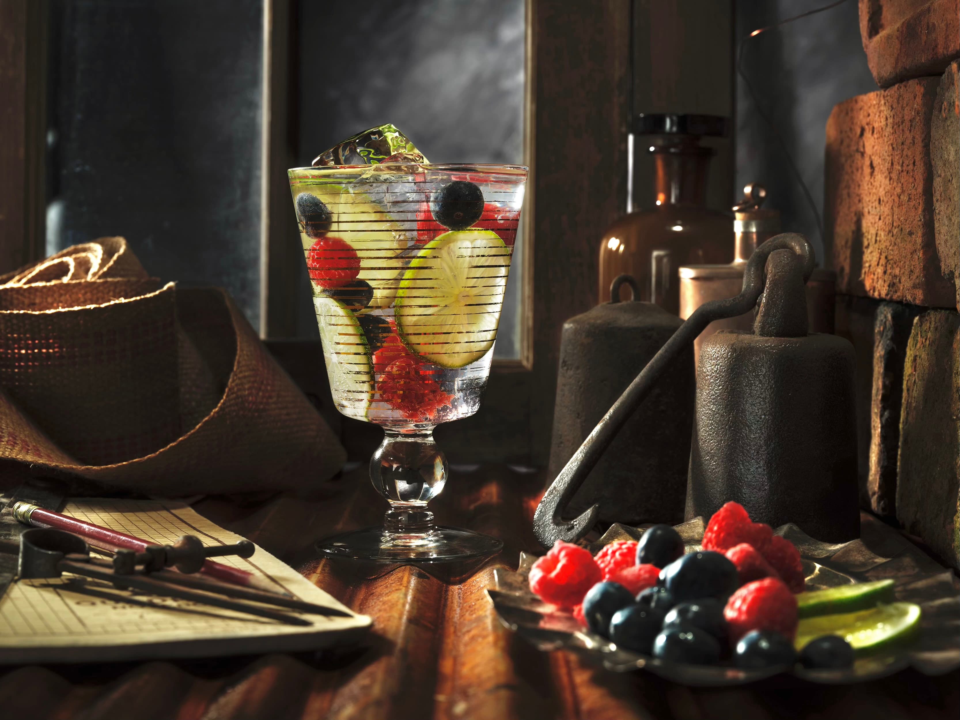 Berry and lime cocktail styled among vintage tools and fruit