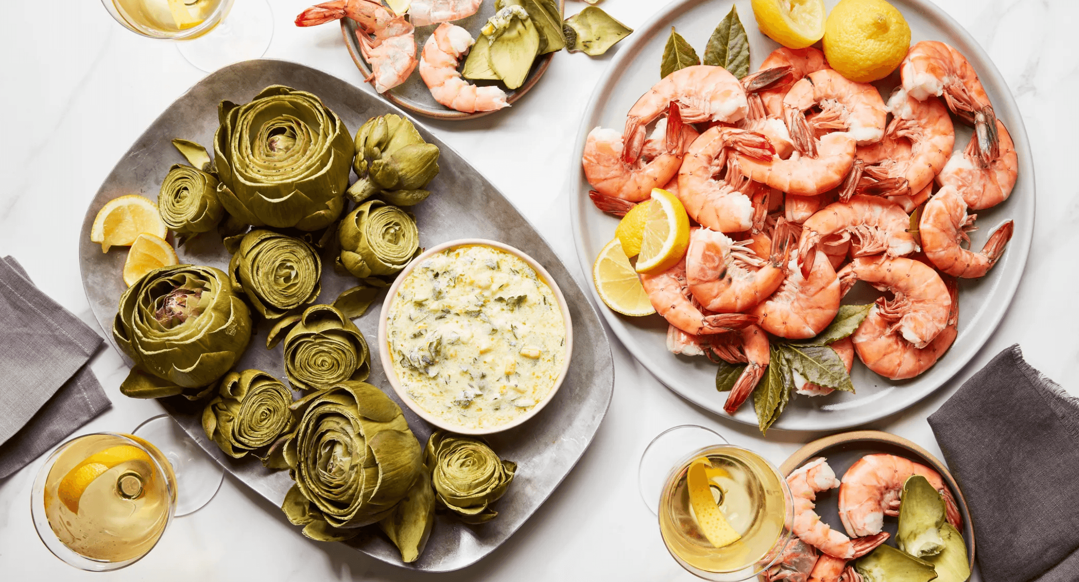 Artichokes, shrimp, lemons, and wine arranged for a festive menu
